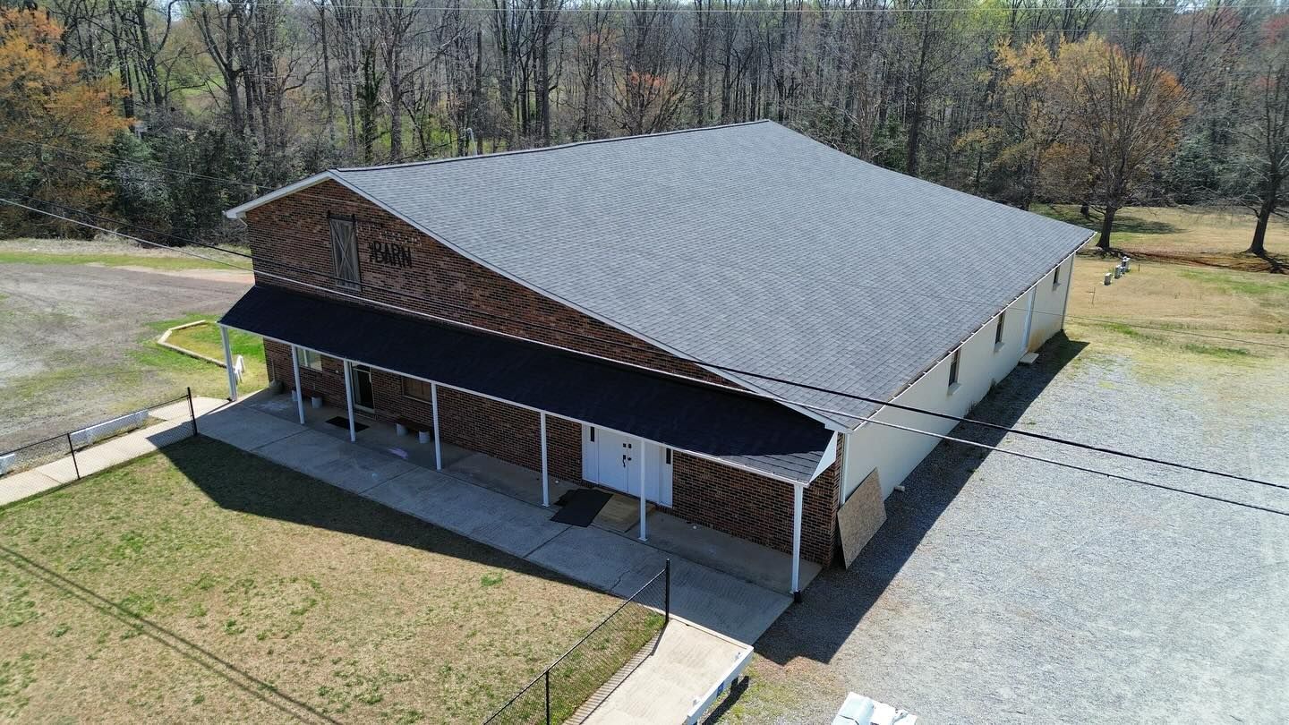 An aerial view of a large building with a black roof and a porch.