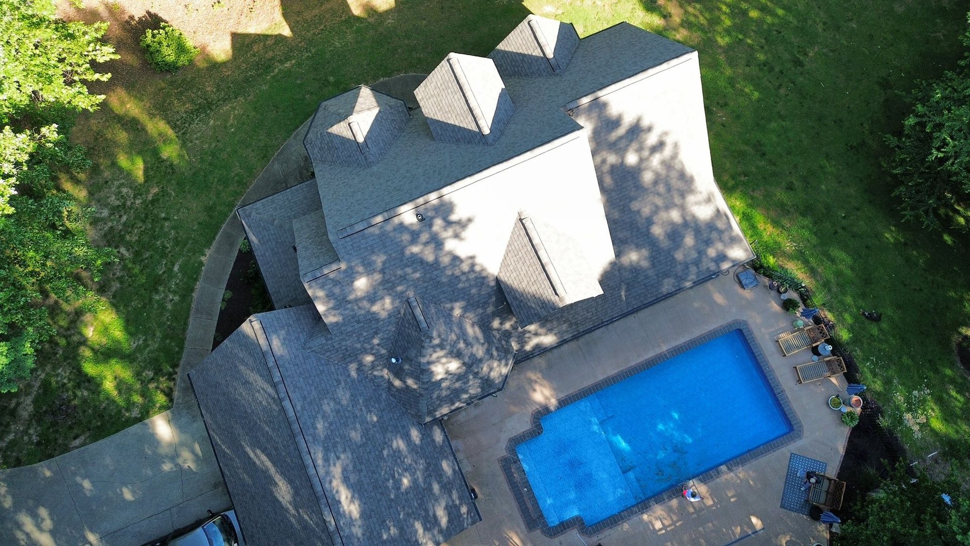An aerial view of a house with a large swimming pool in the backyard.