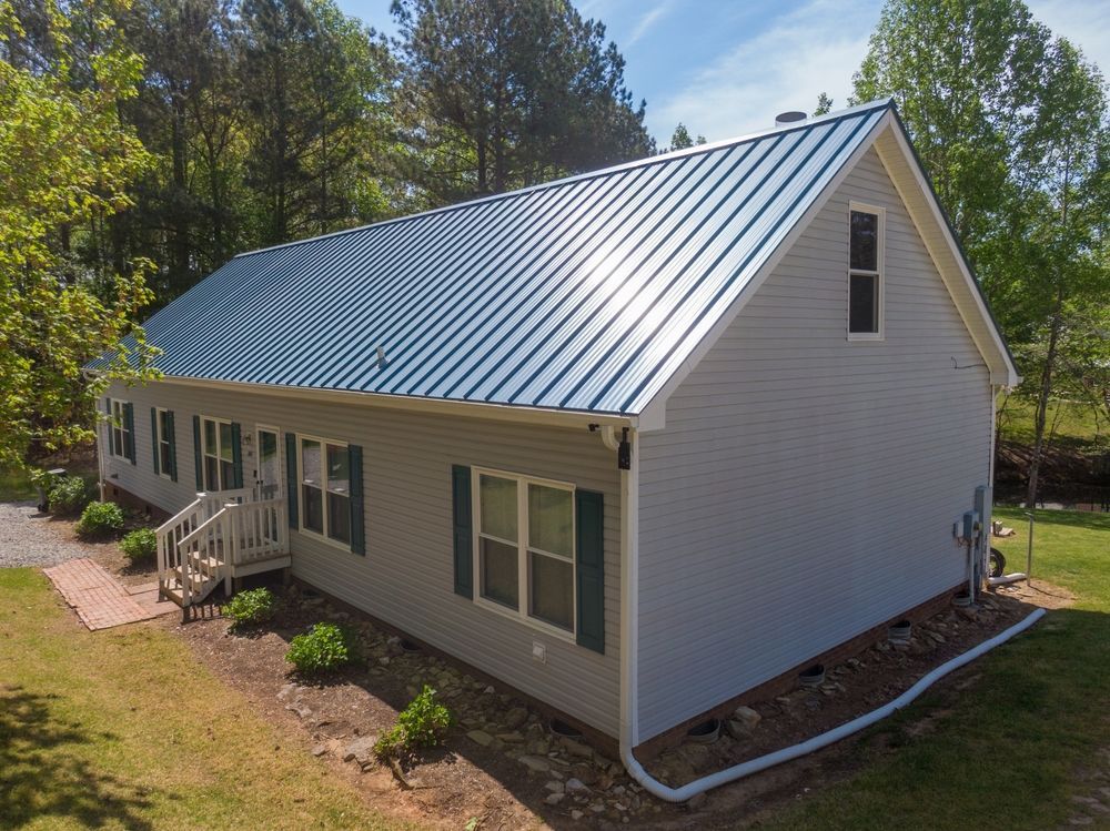 An aerial view of a white house with a blue metal roof.