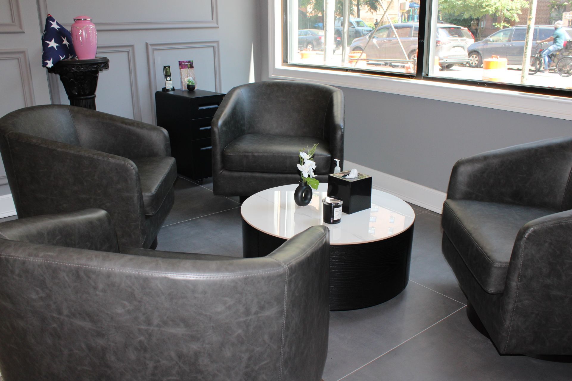 Modern waiting area with dark chairs, a round table, and a window view