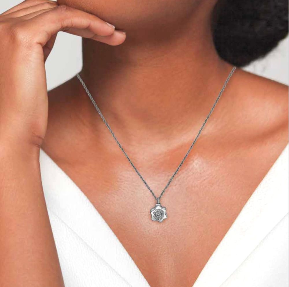 Silver pendant necklace on a person wearing a white top