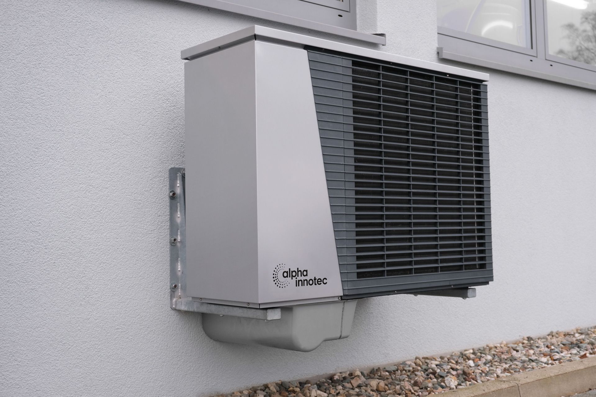 Wall-mounted outdoor air conditioner unit on a light gray exterior wall.