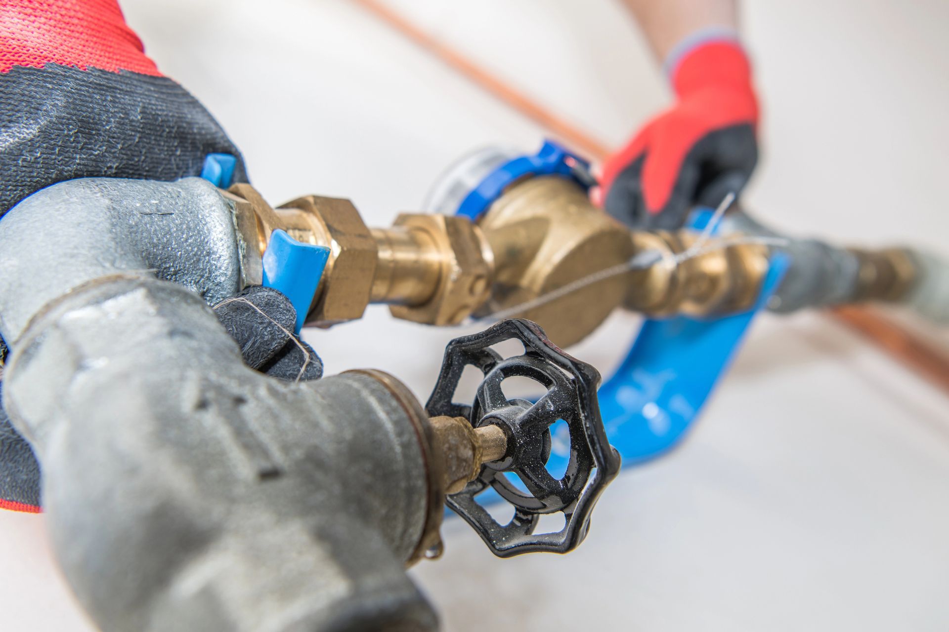 Persona con guanti rossi che lavora sui tubi idraulici con una chiave inglese.