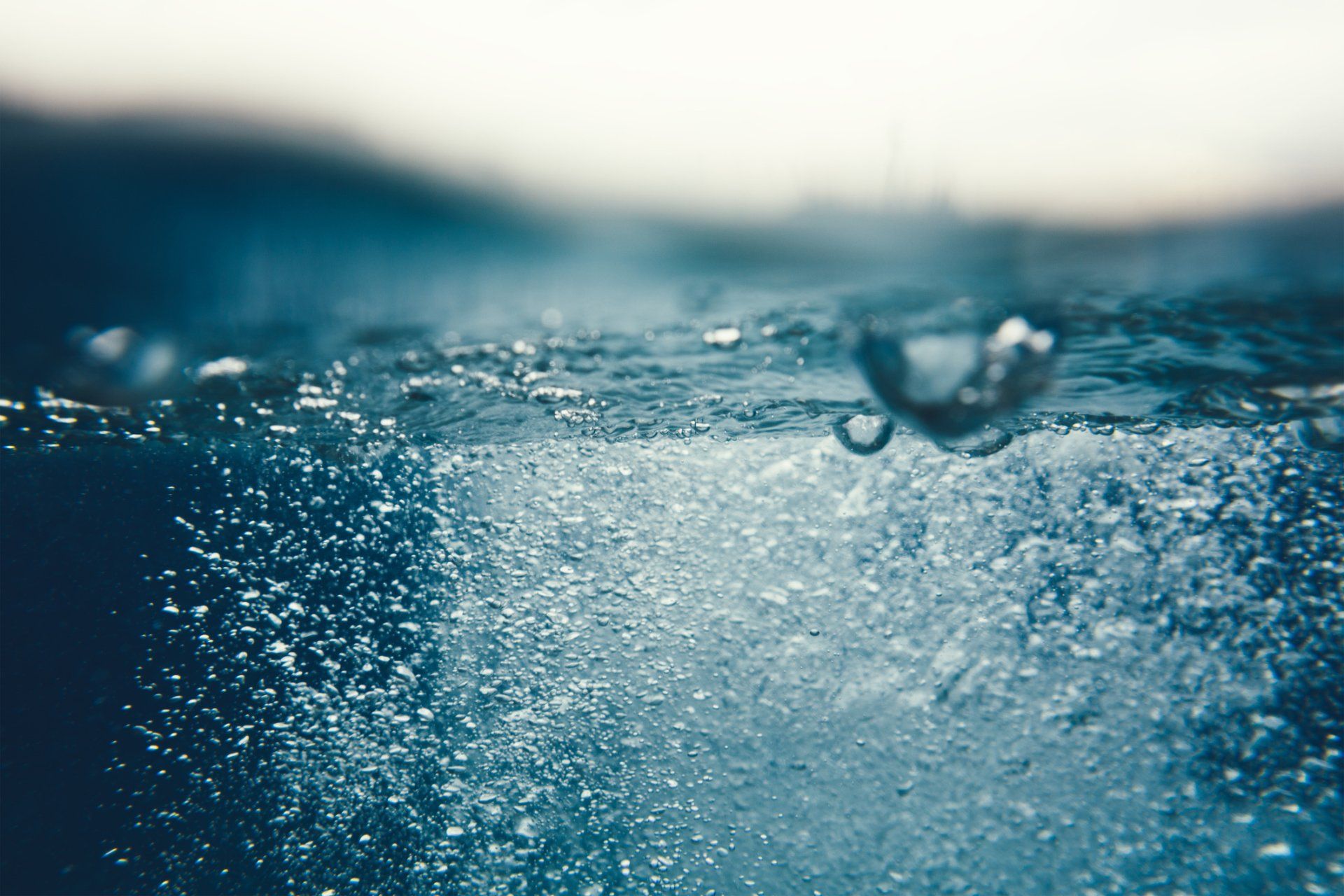 Bolle che salgono sott'acqua, con la superficie visibile dall'alto, in tonalità di blu.