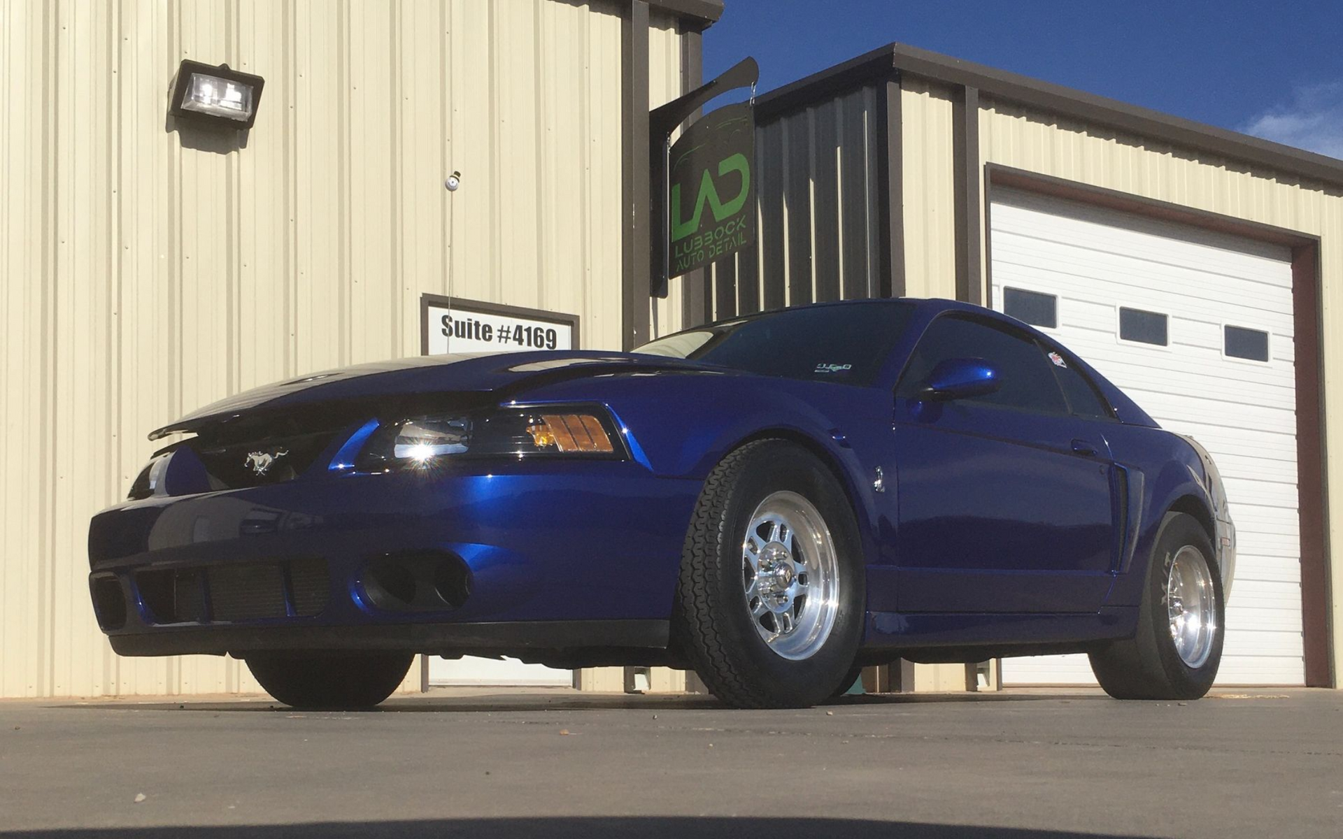 A blue car with flames painted on the hood is parked on the side of the road.