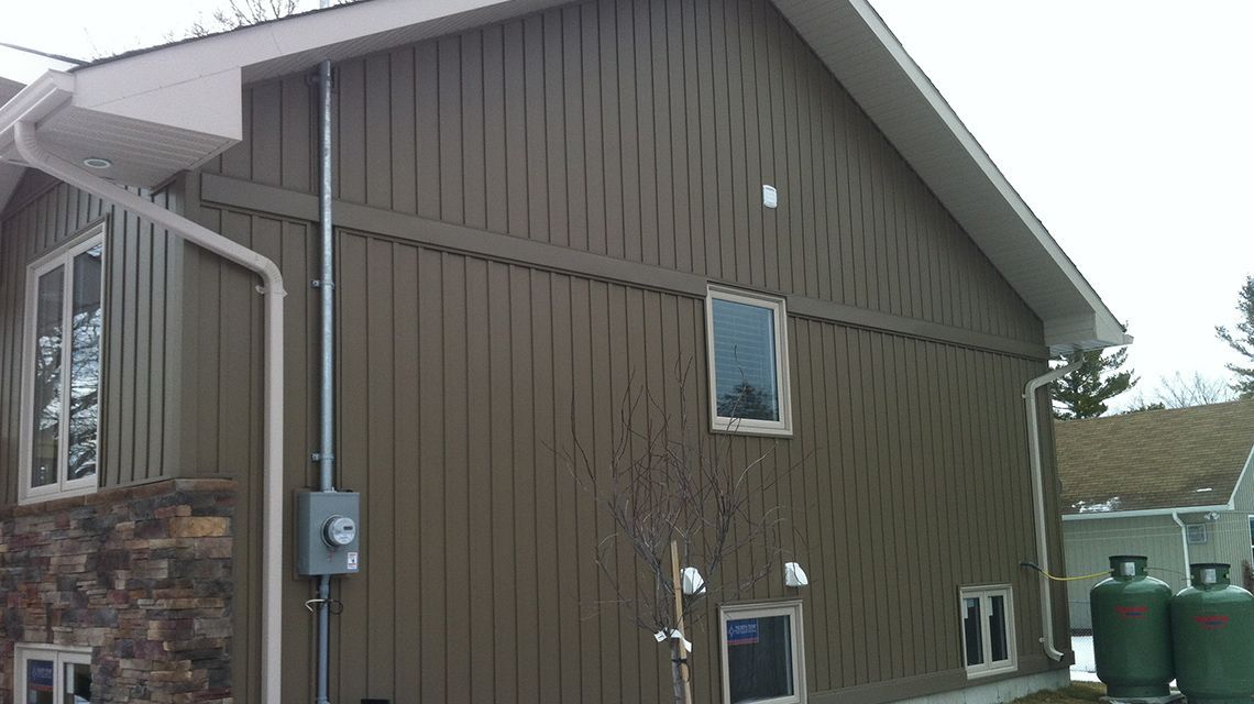 Brown siding on a house with a white roof