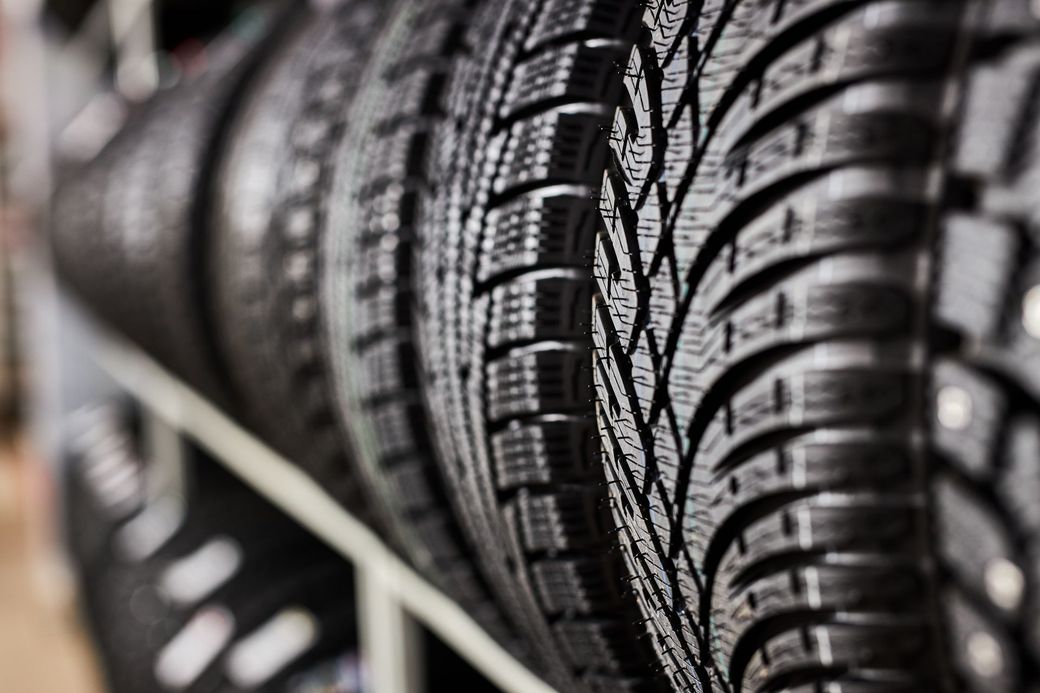 Black and white photo of several tires stacked on a shelf.