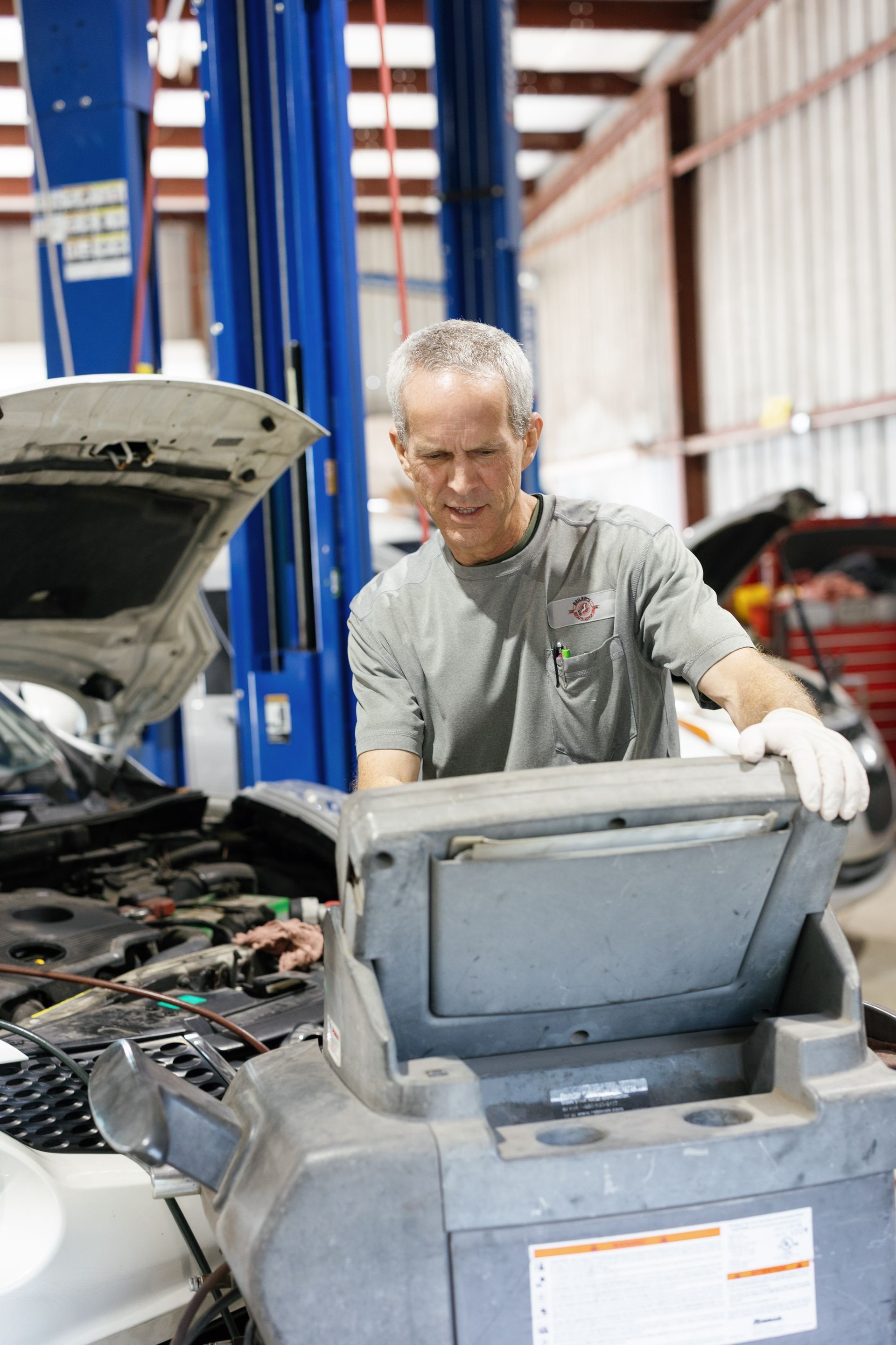 Mechanic working on a car in a shop, using a diagnostic tool.