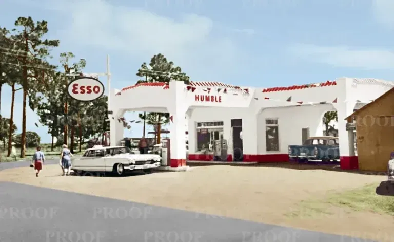 Esso gas station with white car, people, and blue pickup truck in front.