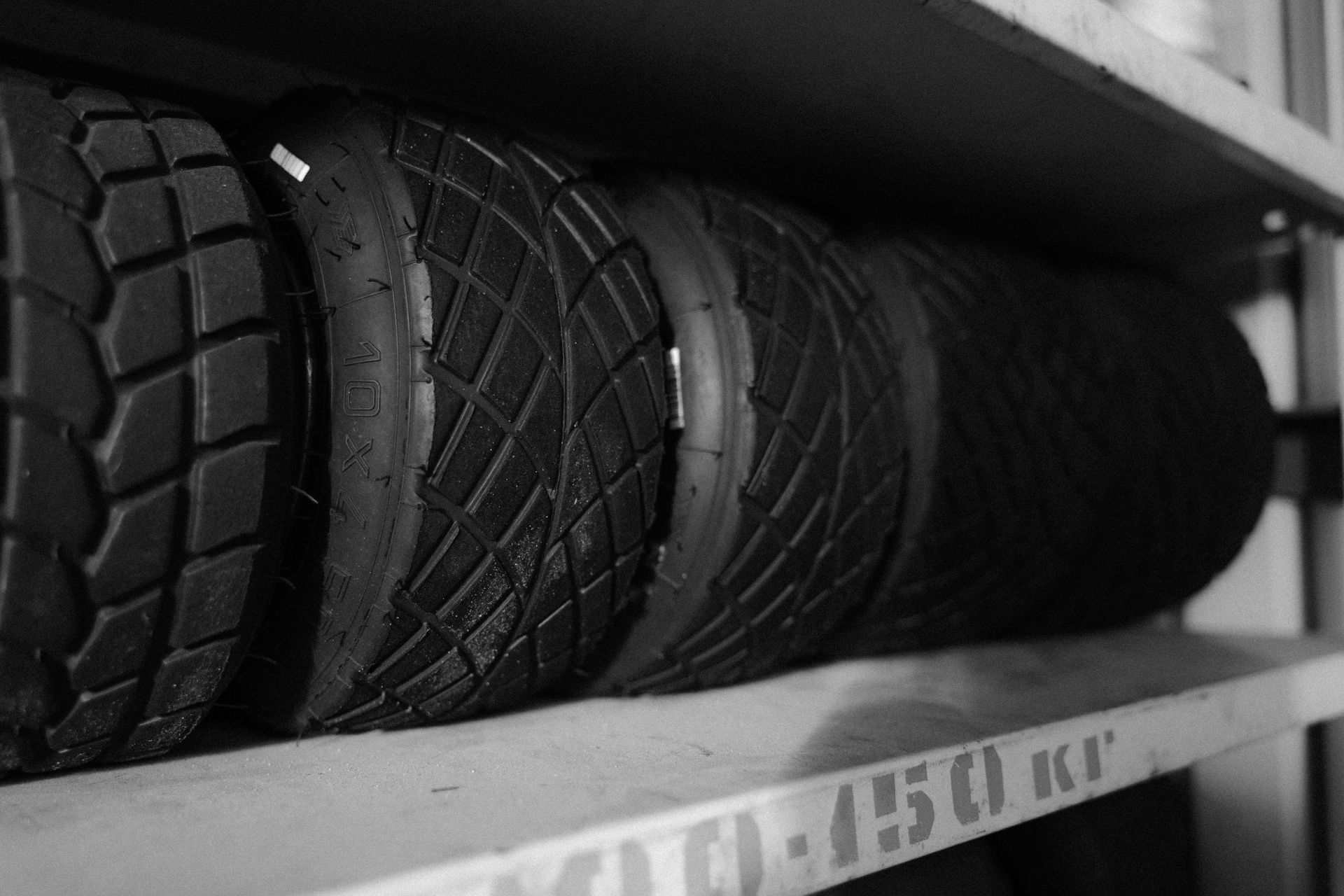 Black and white photo of several tires stacked on a shelf.
