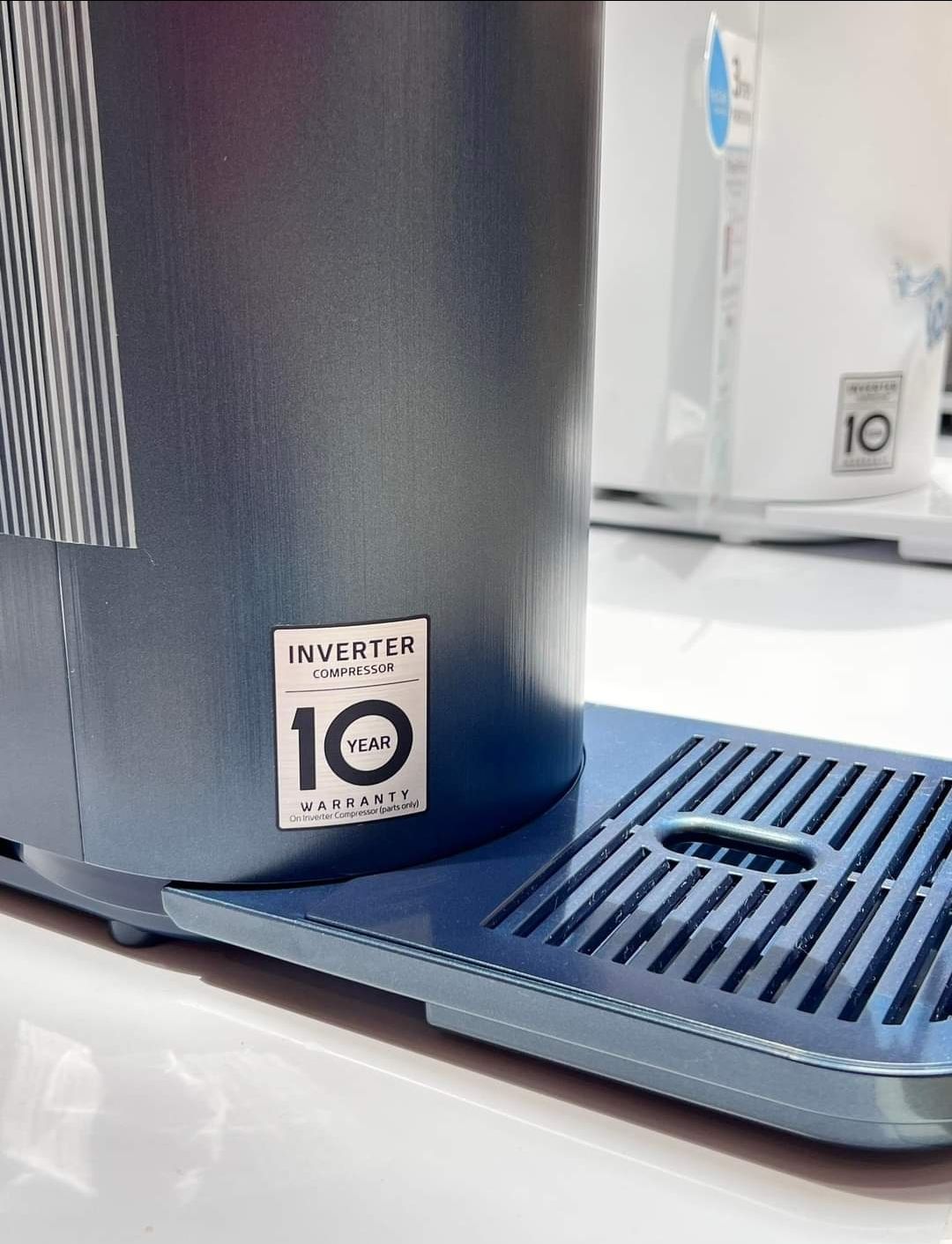 Blue appliance with a 10-year warranty sticker on the side, next to a drainage tray.