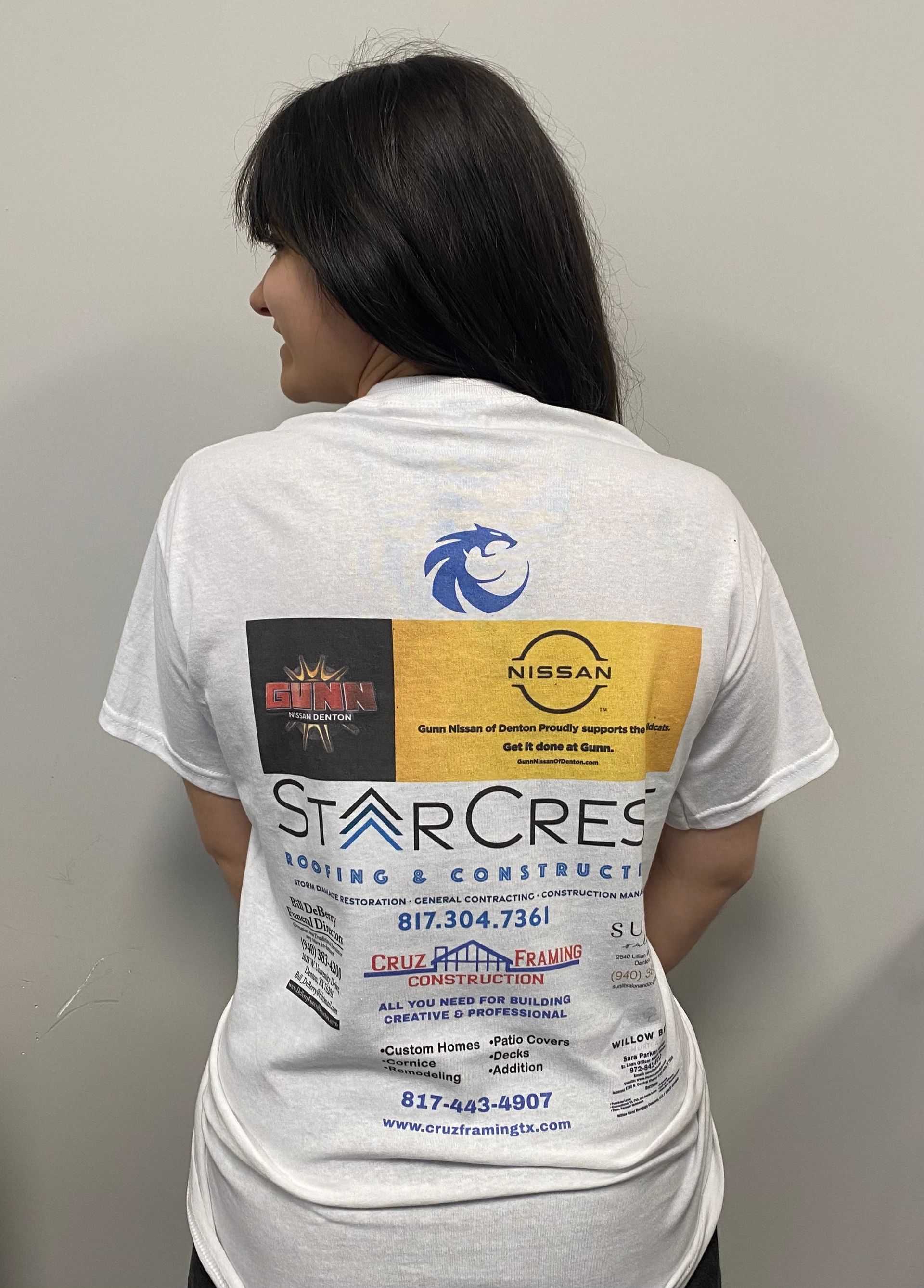 someone wearing a high schools spirit shirt with advertising on the back