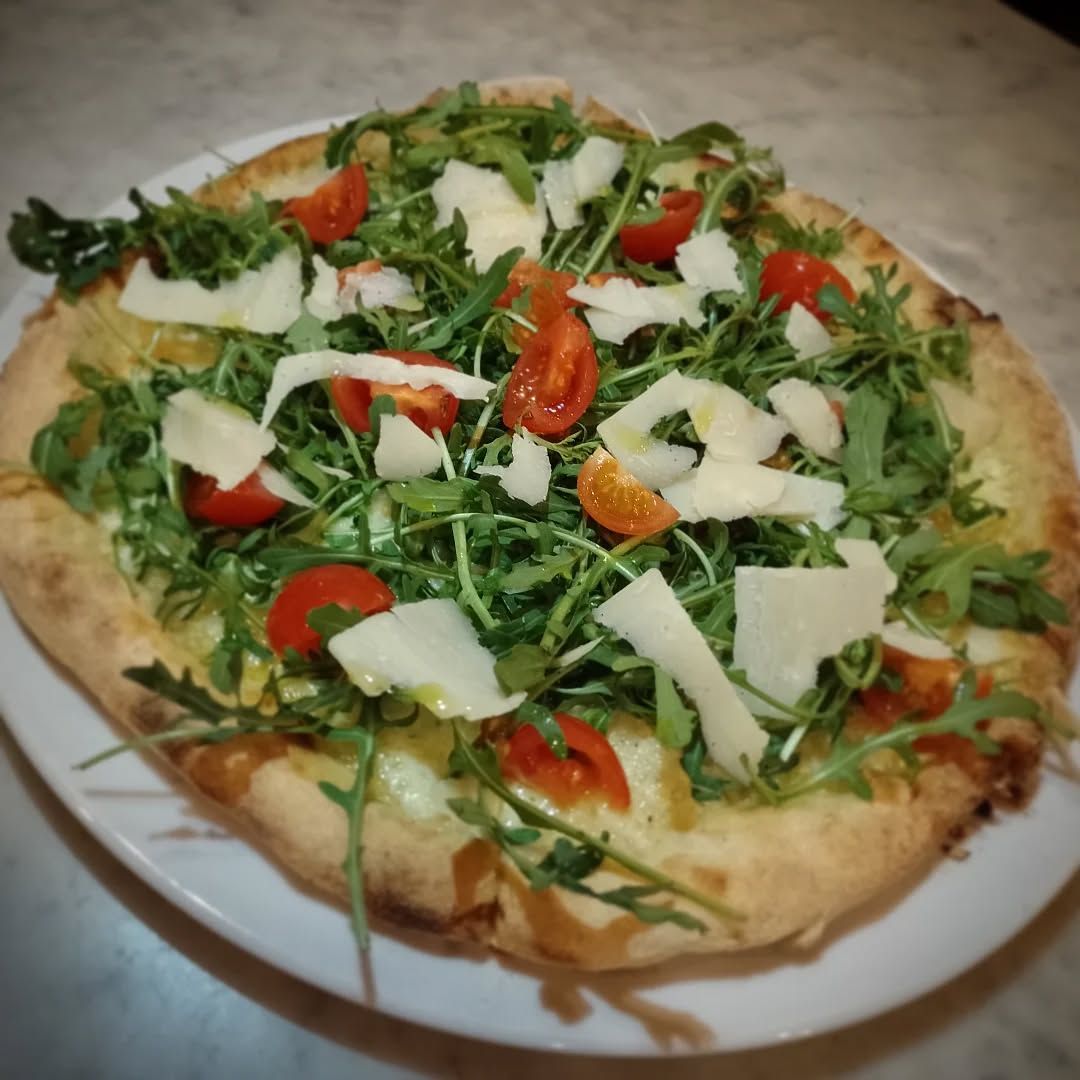 Pizza con rucola, pomodorini, grana