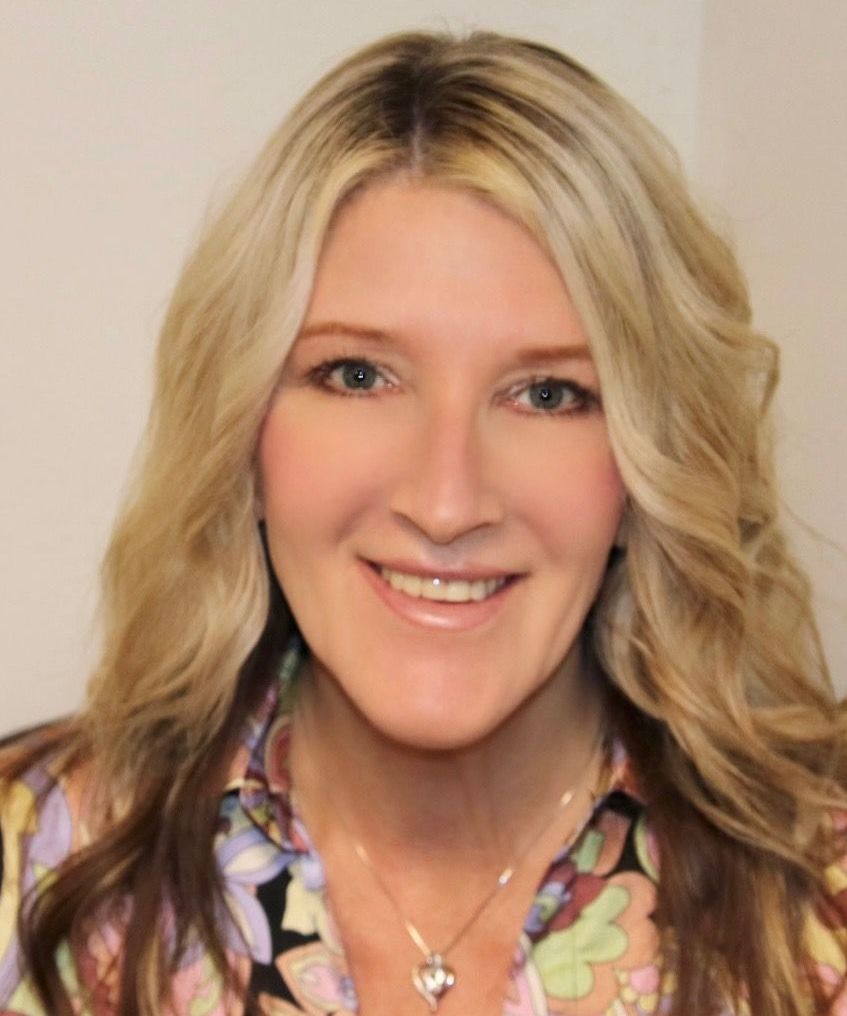 A woman with long blonde hair is smiling for the camera.