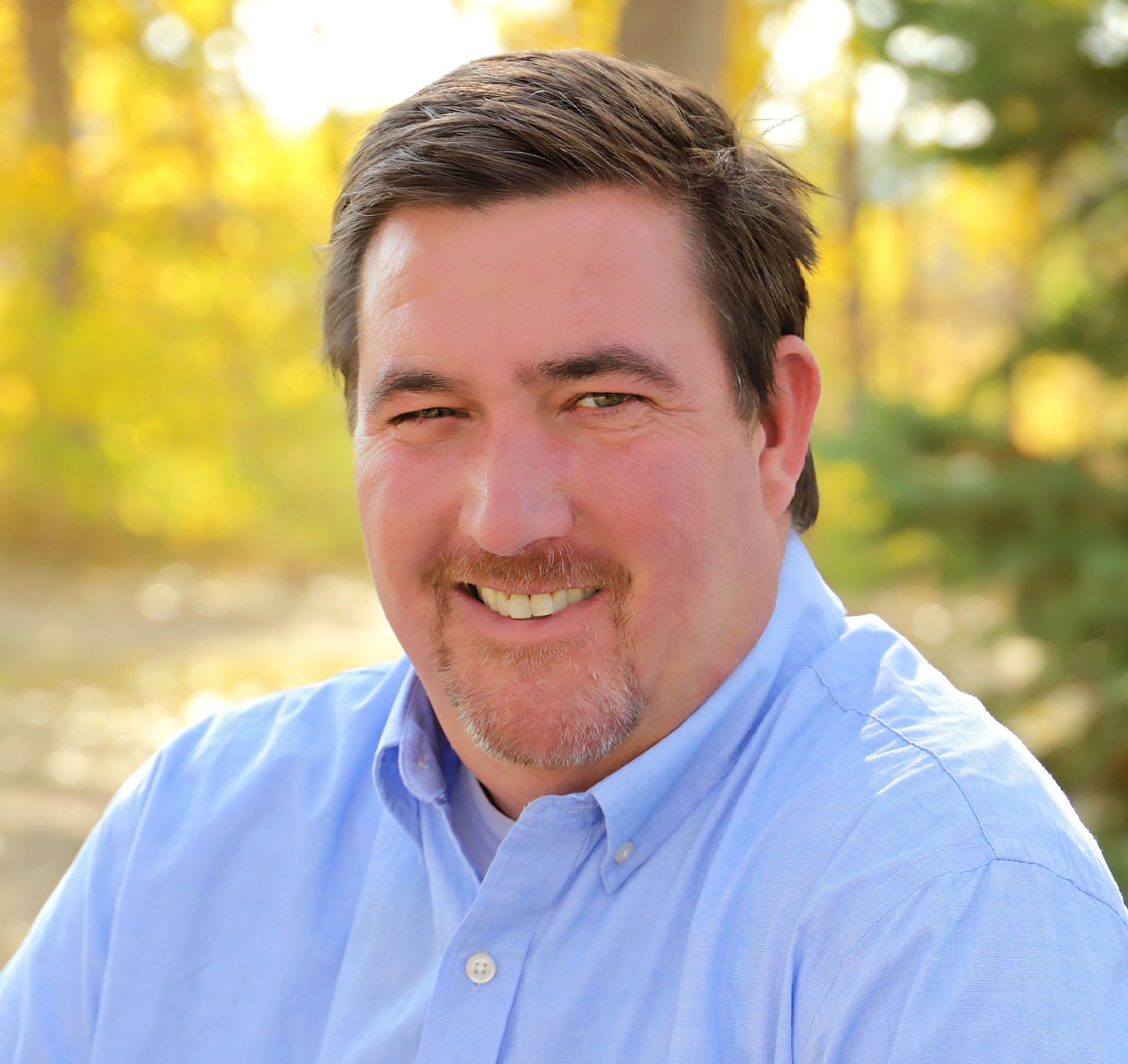 A woman wearing a blue jacket and a blue shirt is smiling for the camera.