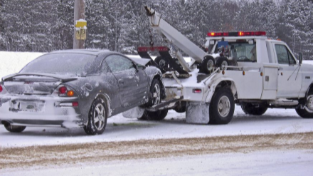 Picture of a silver car being towed away in the snow by Towing Coquitlam.