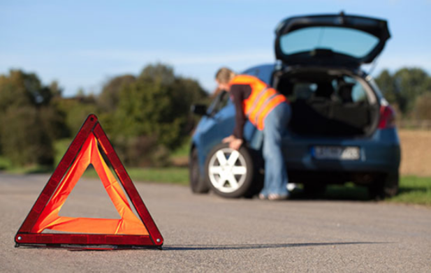 Picture of a women rolling out a spare tire to be installed on her vehicle.