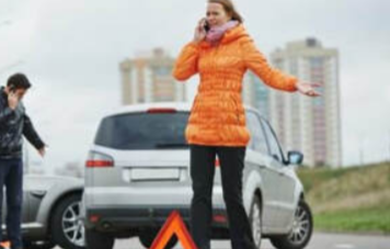 Picture of a women in an orange jacket and a man in a black jacket calling for towing after a car accident with each other.