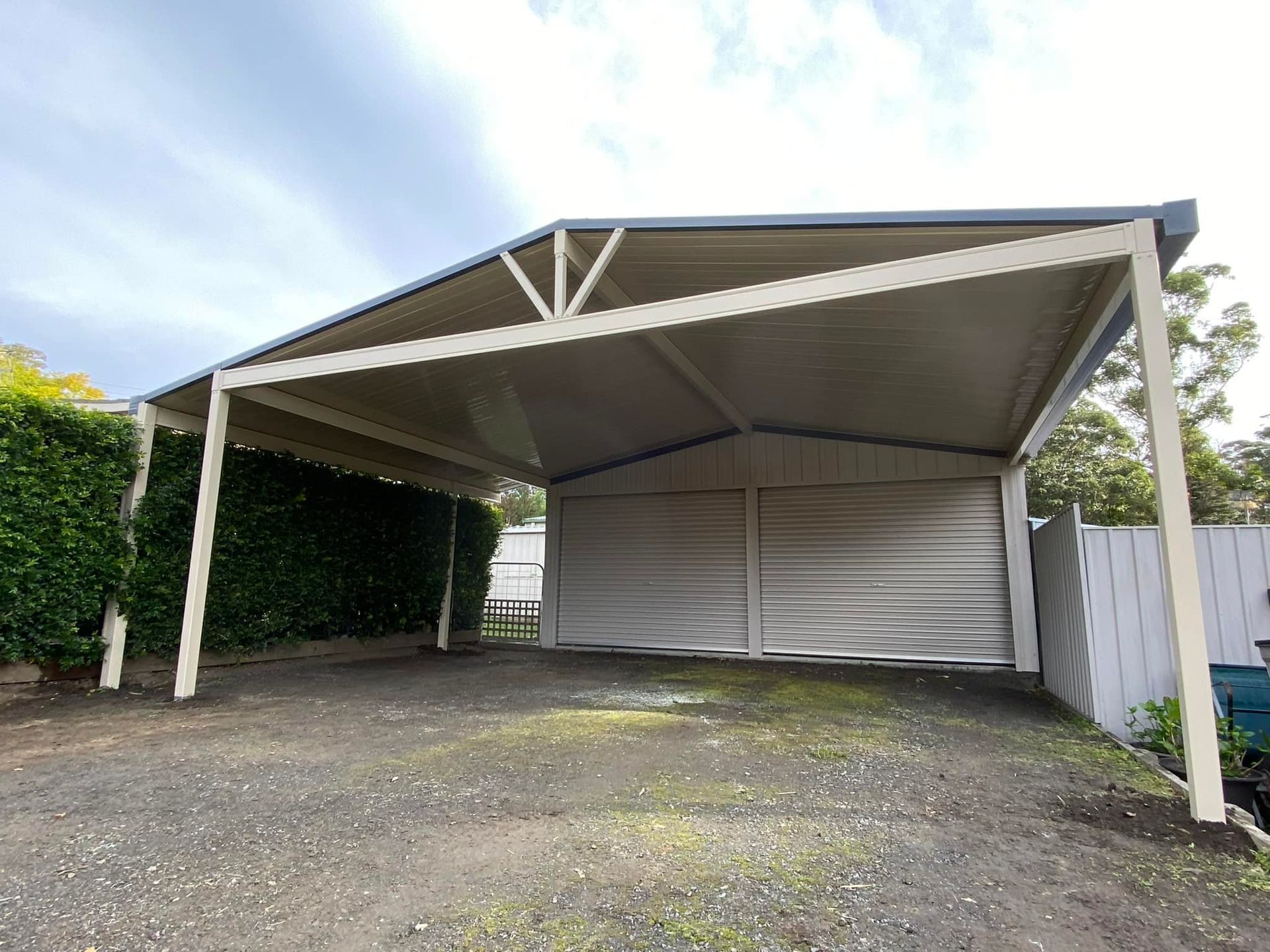 A white patio cover is being installed on the side of a brick house.