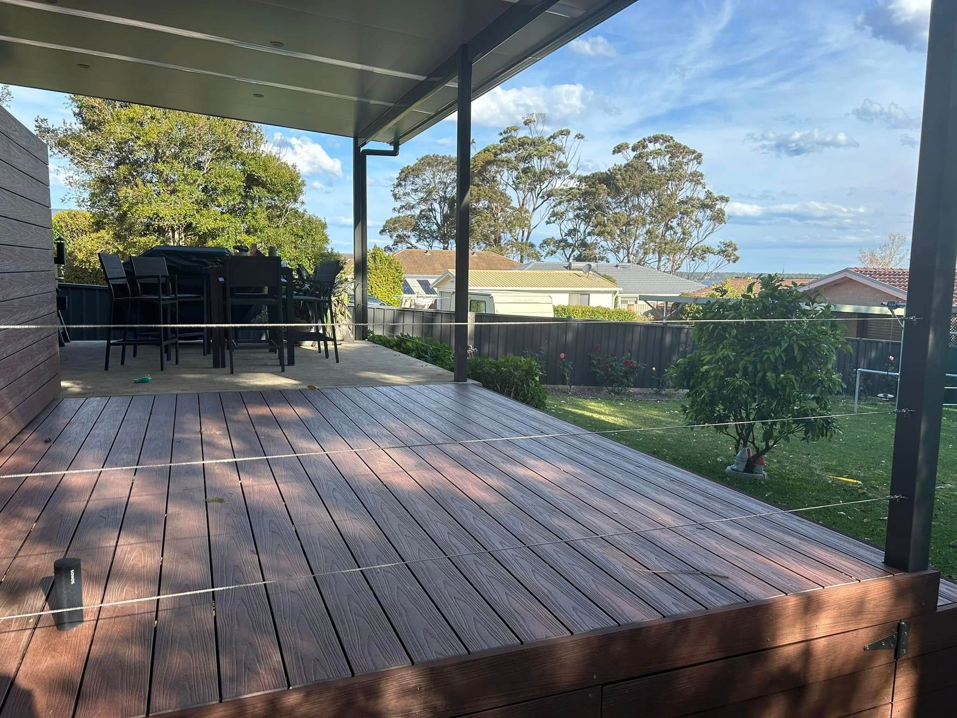 Wooden deck surrounds a small rectangular pool in a backyard.