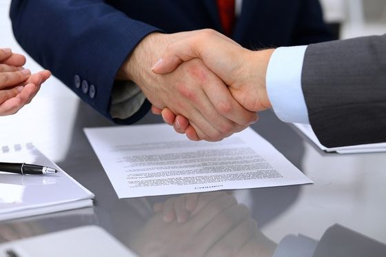 Due mani che si stringono dopo la firma di un contratto