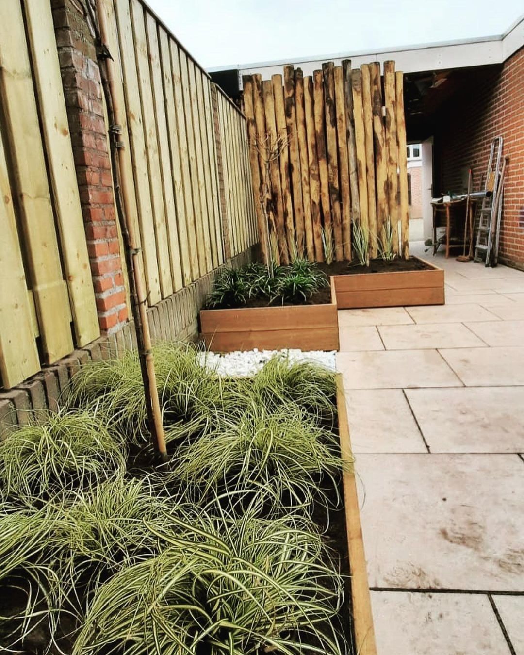 Een terras met een houten hek en plantenbakken.