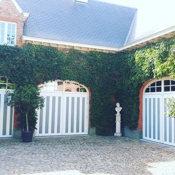 Een huis met twee garagedeuren en een standbeeld ervoor