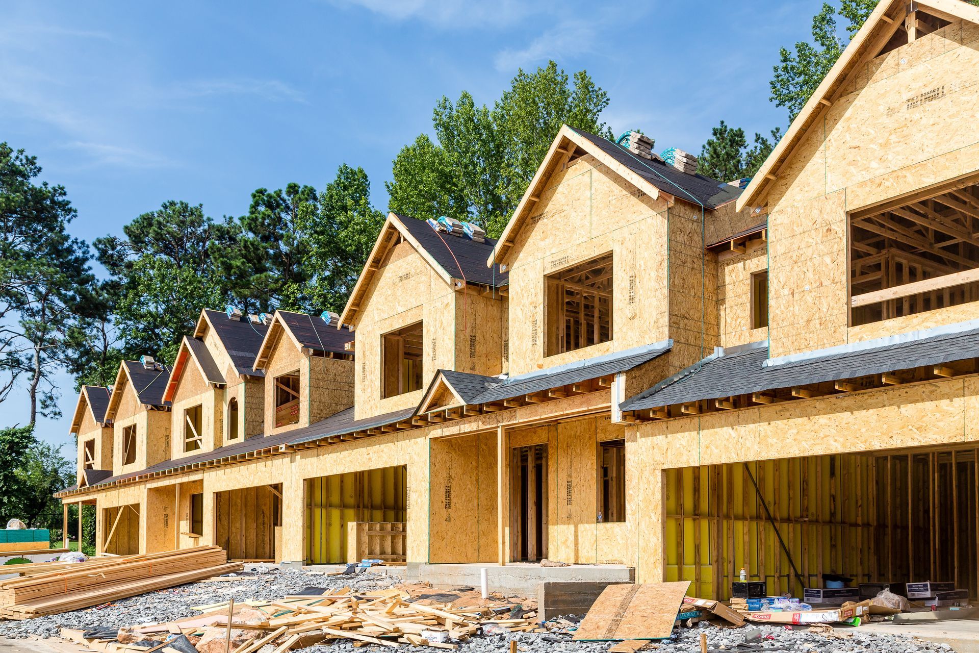 A row of wooden houses are being built on a construction site.