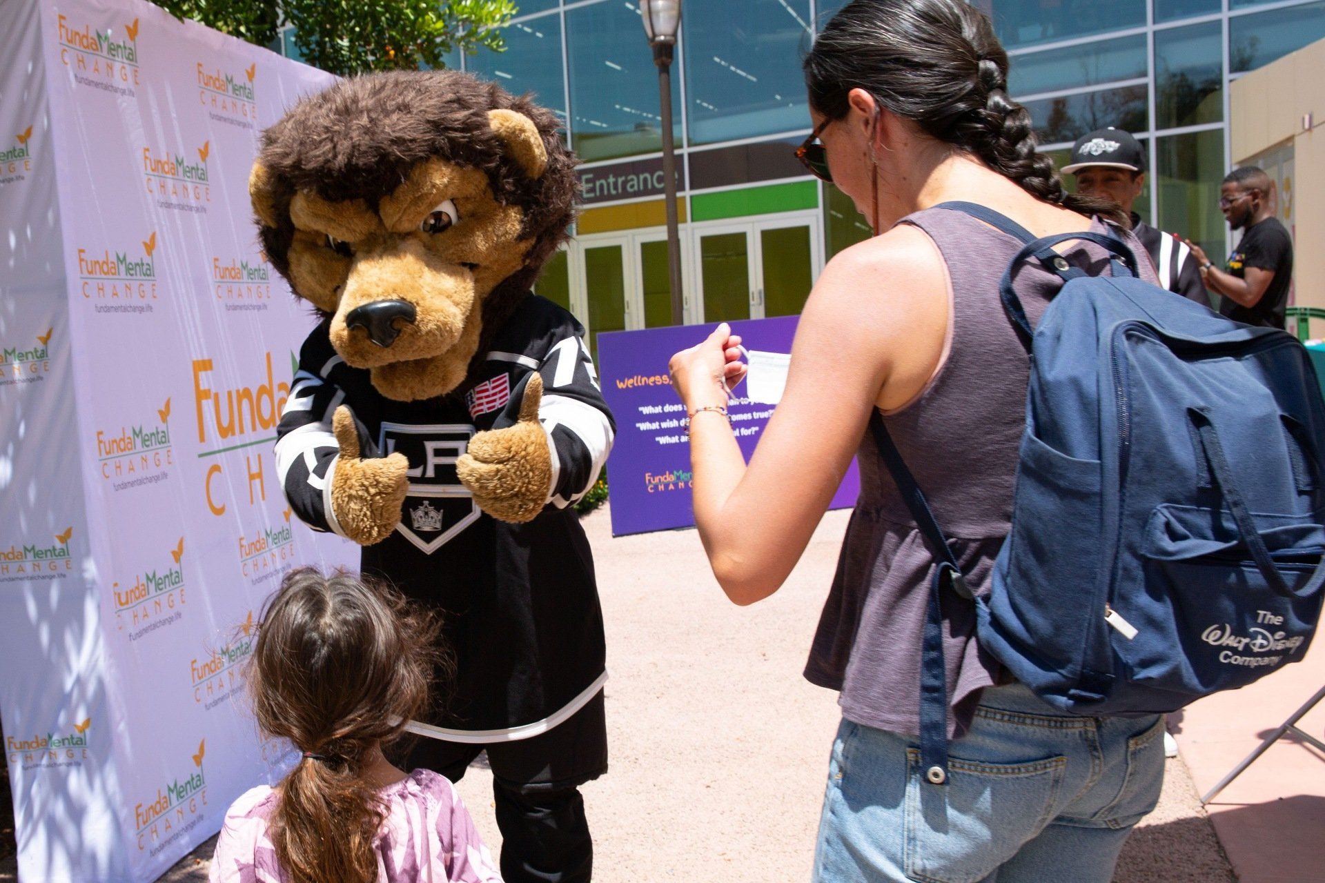 A woman is taking a picture of a lion mascot.