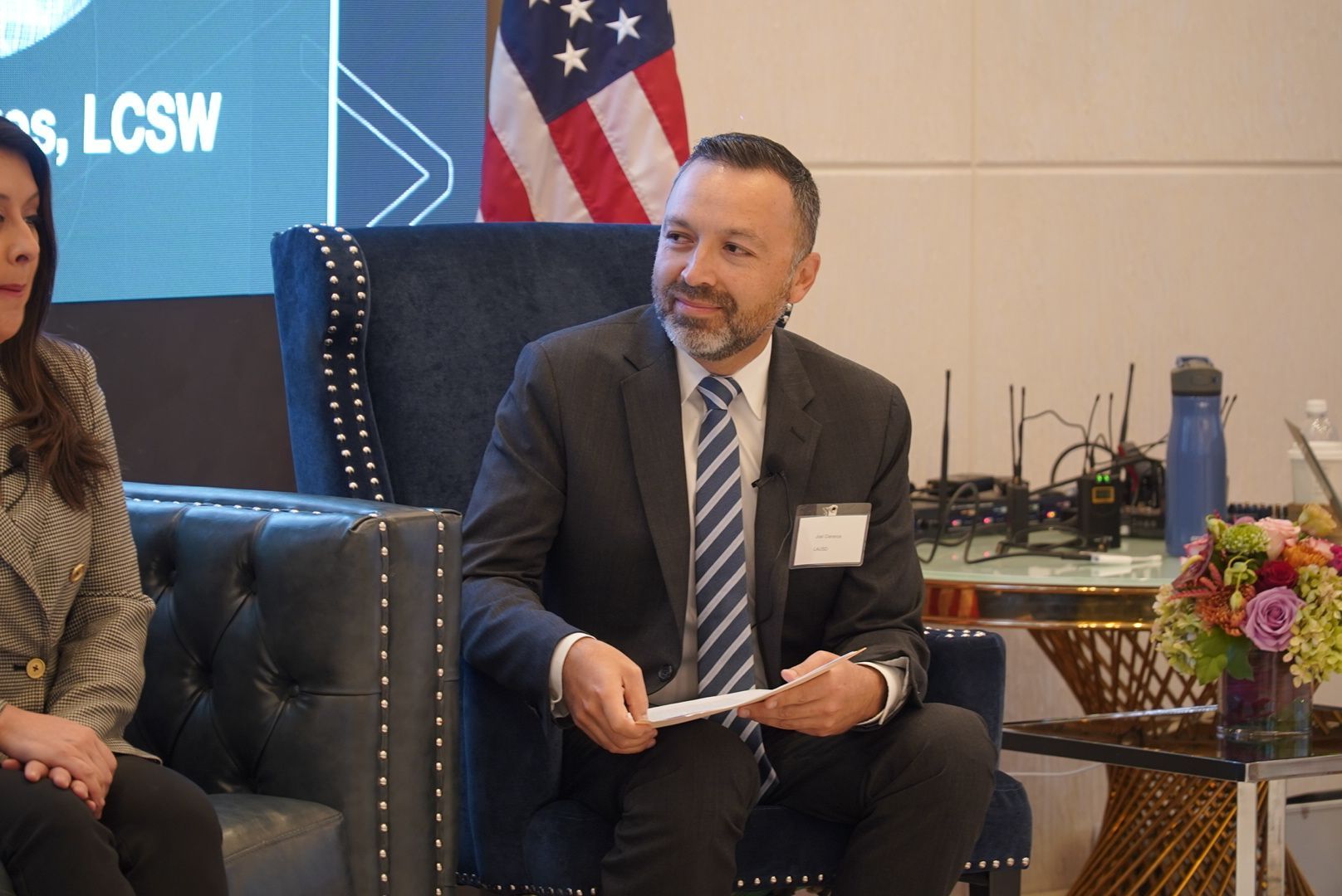 A man in a suit and tie is sitting in a chair holding a piece of paper.
