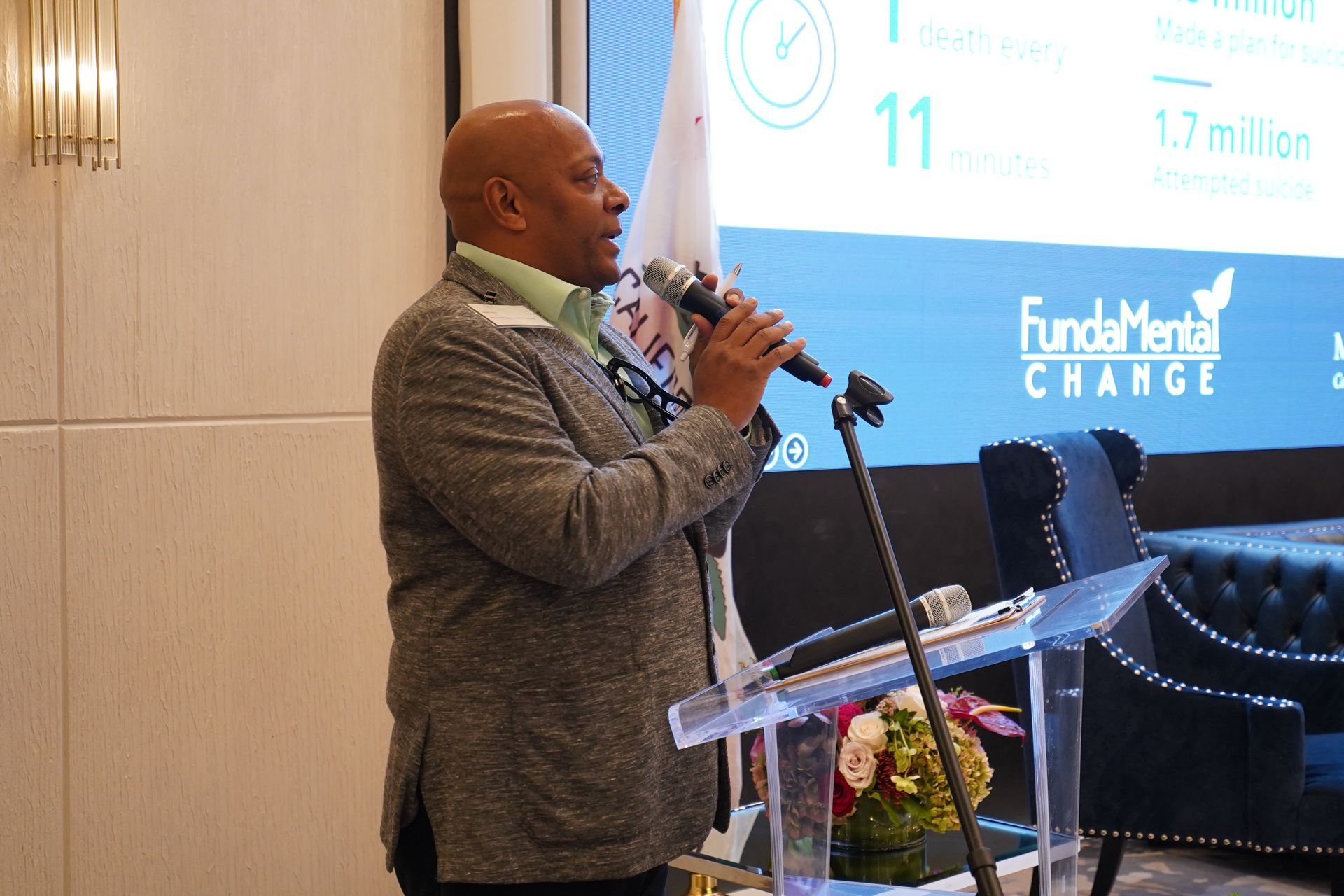 A man is standing at a podium holding a microphone.