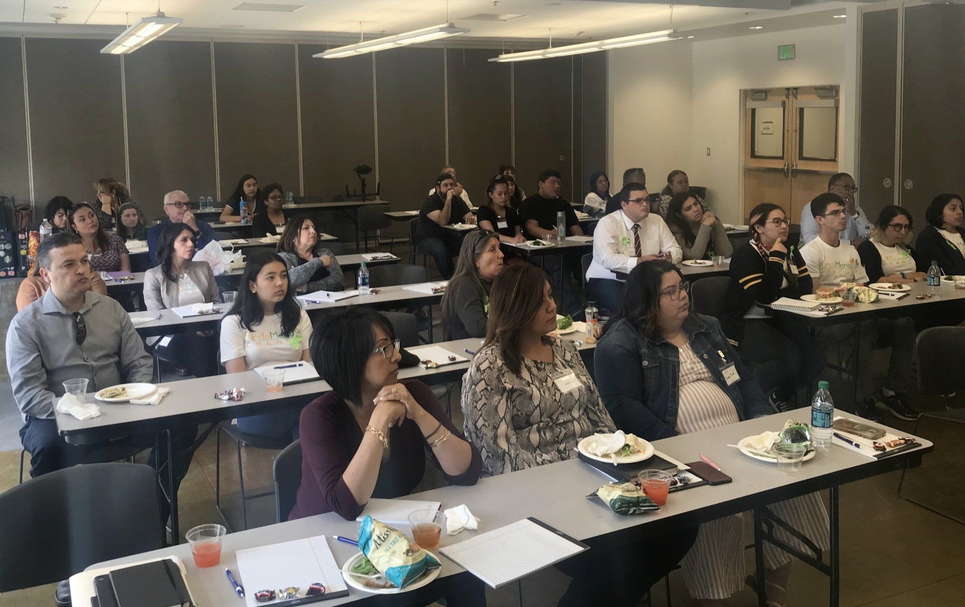 A group of people are sitting at tables in a classroom.