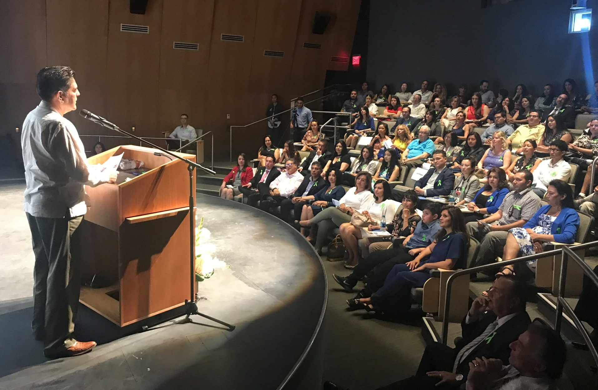 A man is giving a speech at a podium in front of a crowd of people.