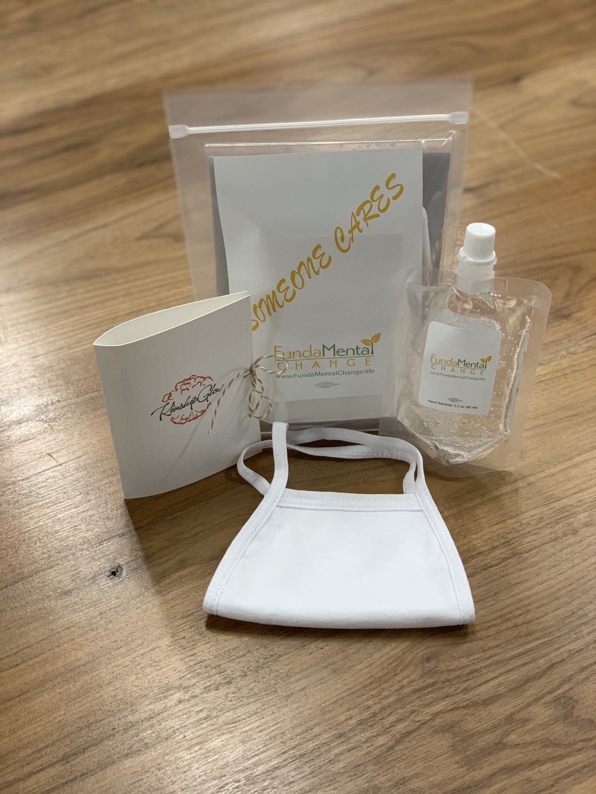 A white face mask is sitting on a wooden table next to a bag of soap and a bottle of hand sanitizer.