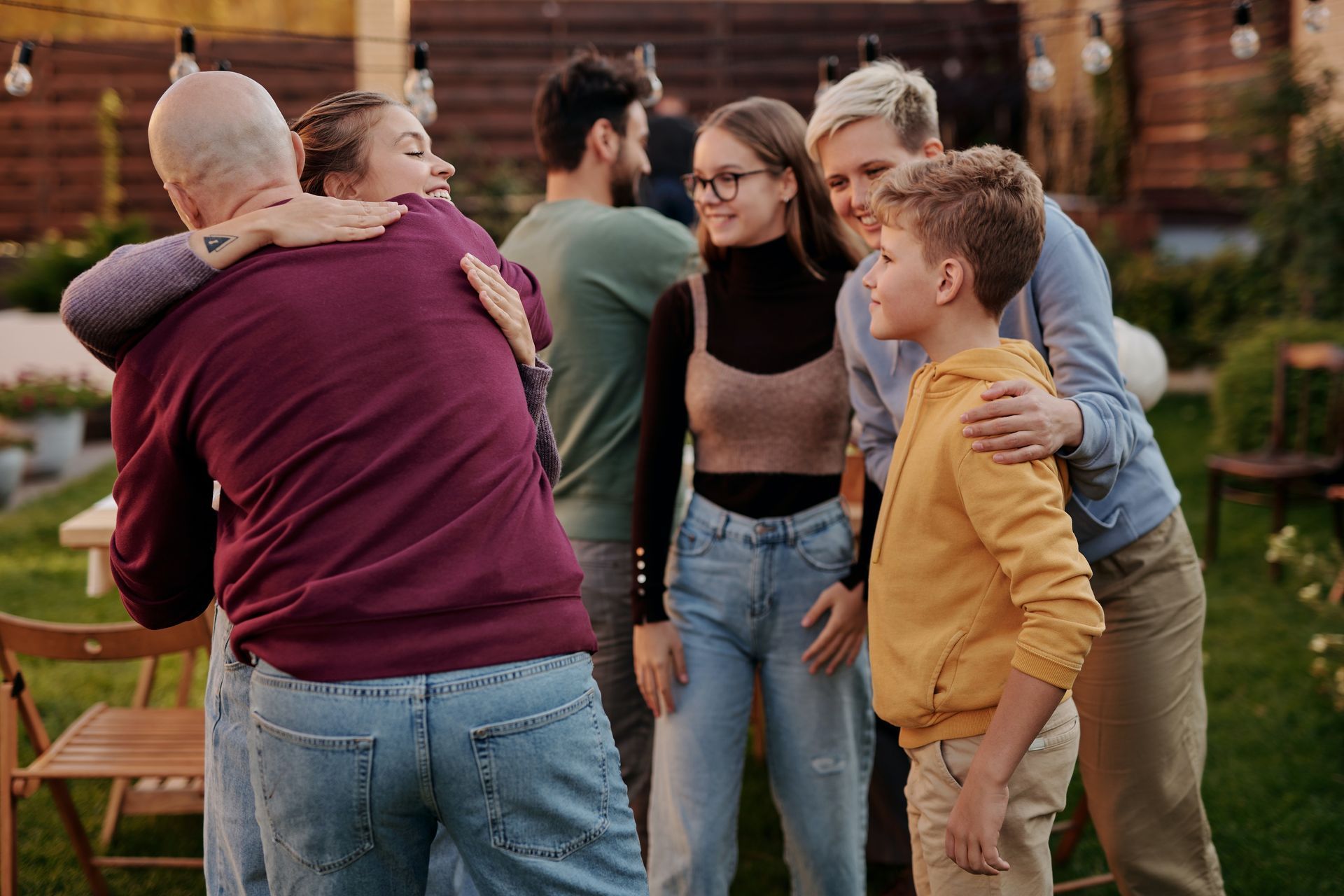 a group of people are hugging each other in a backyard