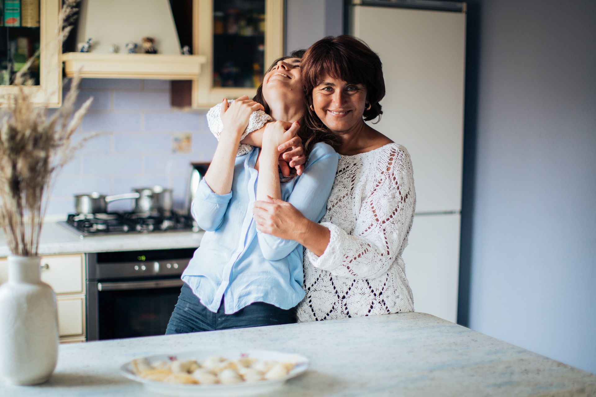 a woman is hugging a young girl in a kitchen
