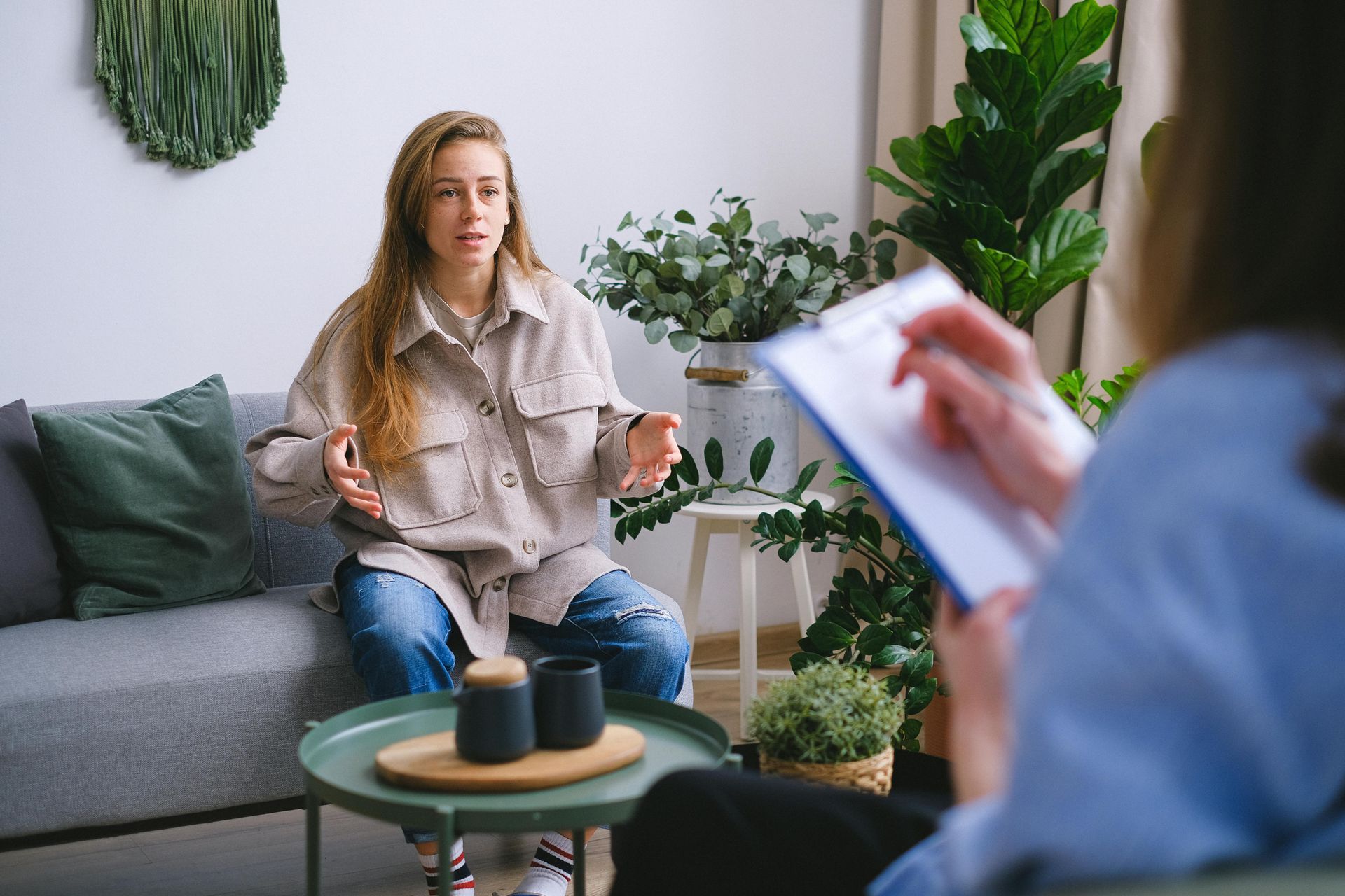 A woman is sitting on a couch talking to a therapist.