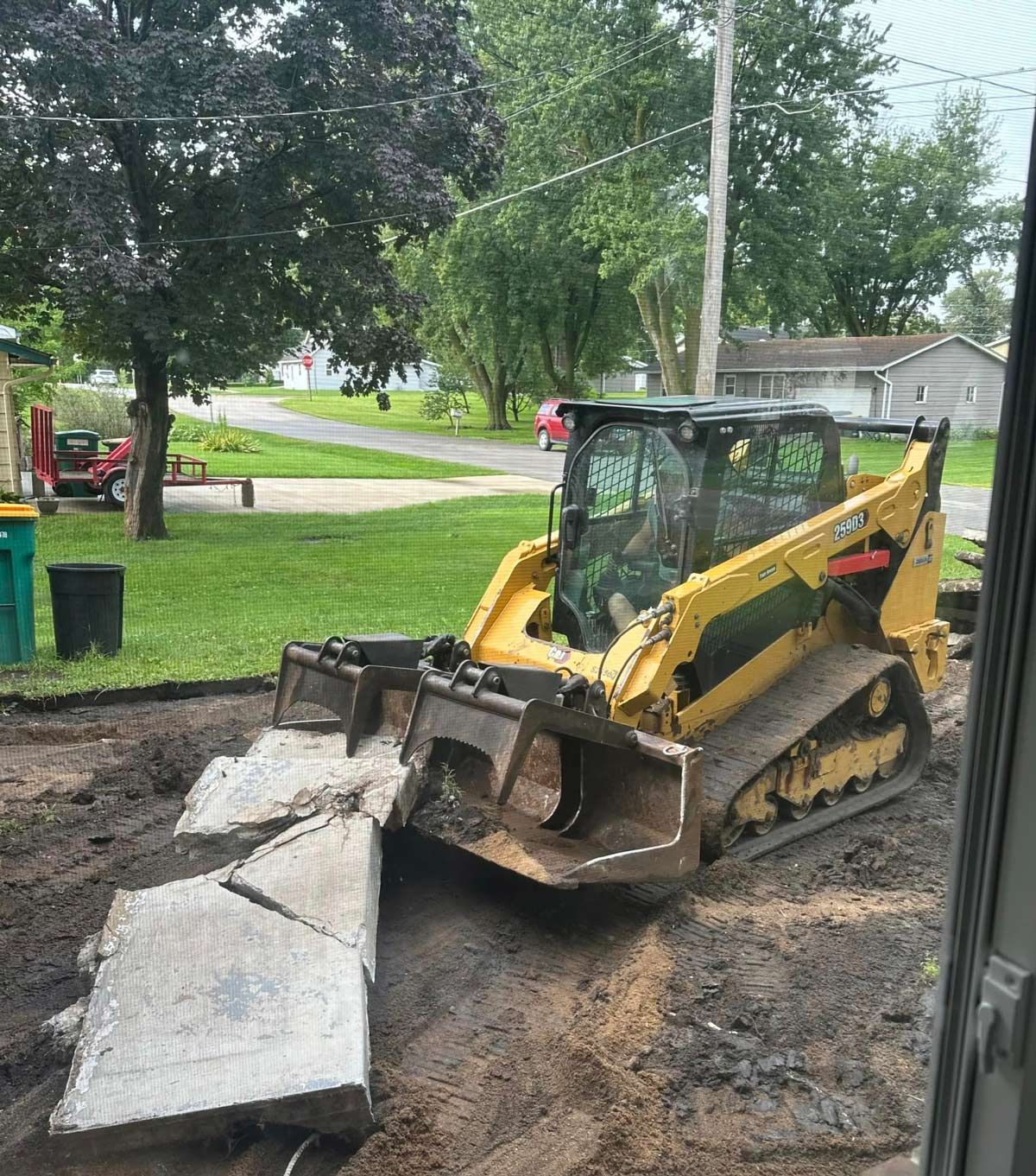 A yellow bulldozer is moving concrete blocks in a yard