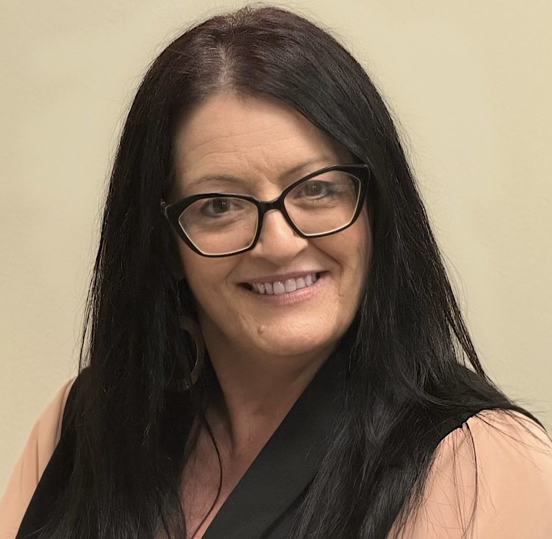 A woman in a suit and white shirt is smiling for the camera.