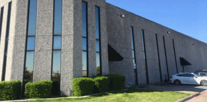 A large concrete building with a lot of windows and a car parked in front of it.