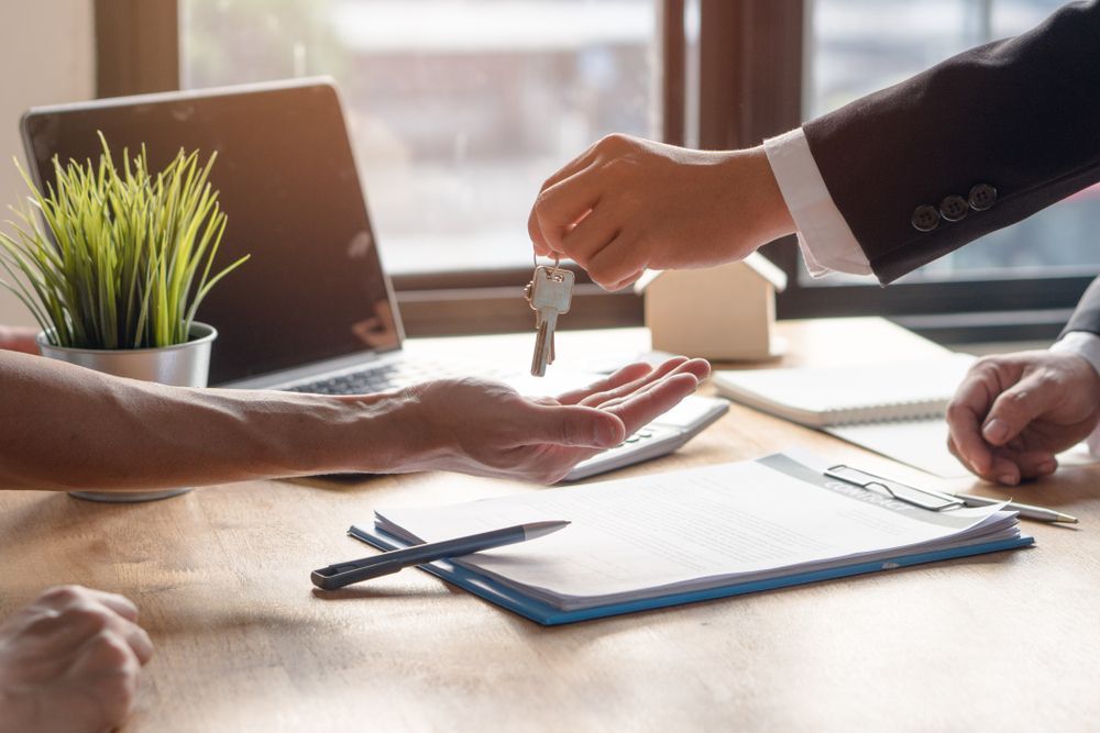 Hands Exchanging Car Keys Over a Desk with Documents, Laptop — Rauseo Group in Zuccoli, NT