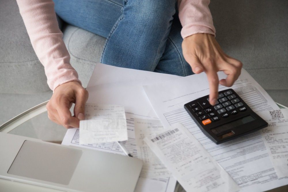 A Woman is Sitting on a Couch Using a Calculator — Rauseo Group in Zuccoli, NT