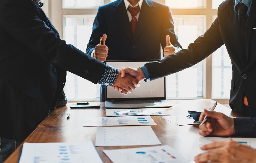 Businesspeople Shaking Hands Across a Conference Table in A Bright Office — Rauseo Group in Zuccoli, NT