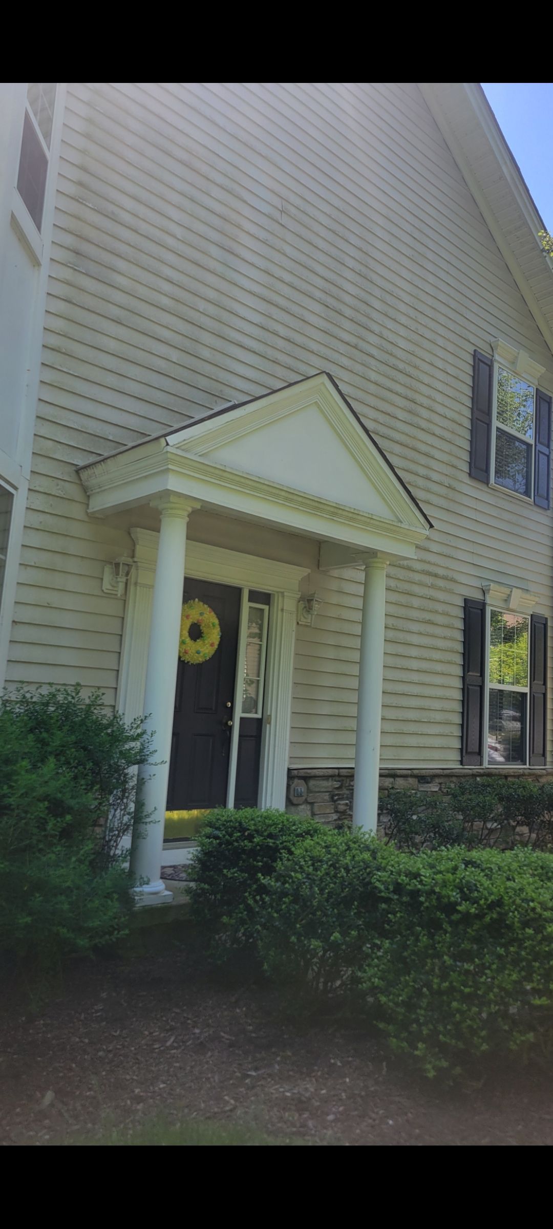 The front of a house with a porch and a wreath on the door.