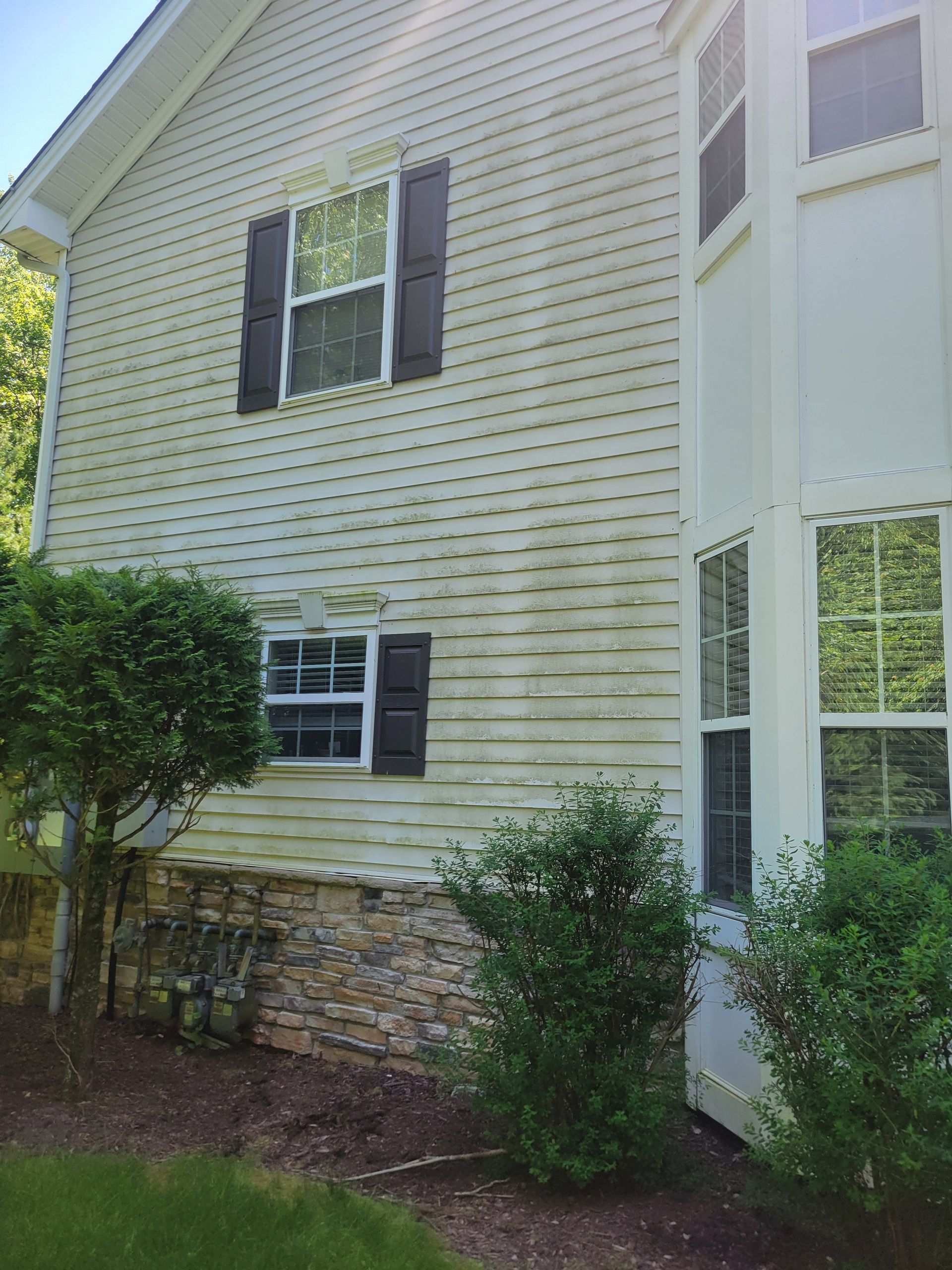 A white house with black shutters and a lot of windows.