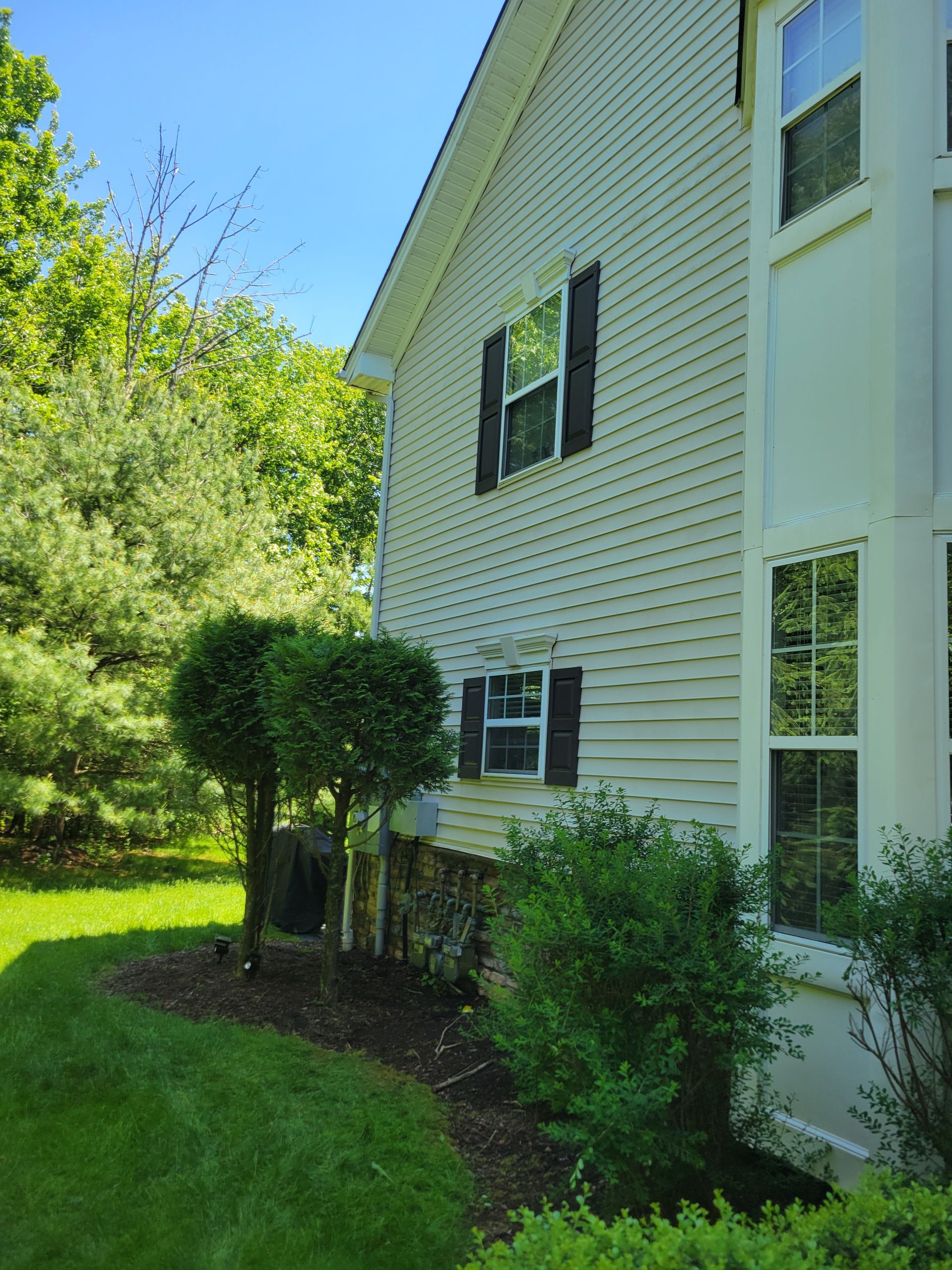 A white house with black shutters and a lush green yard