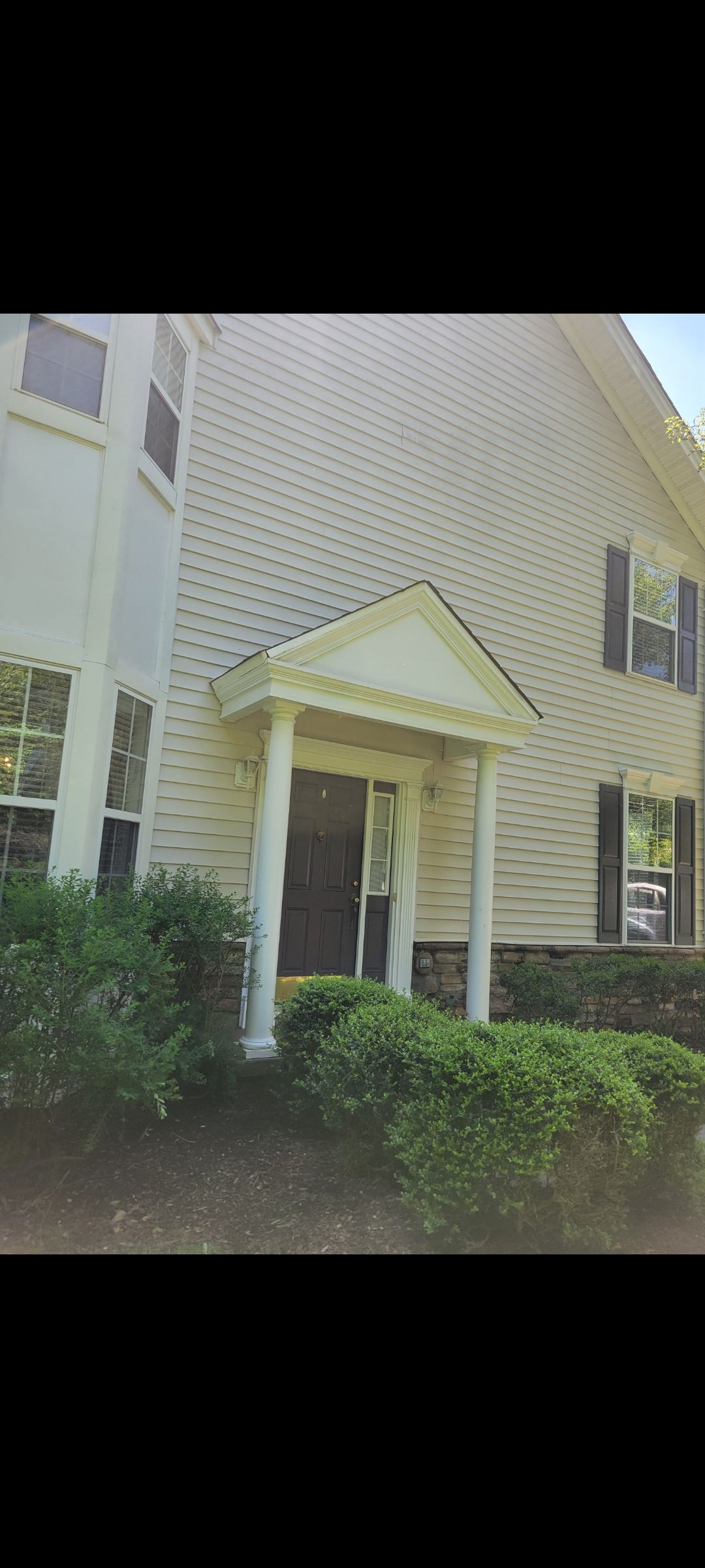 A large white house with a porch and a lot of windows.