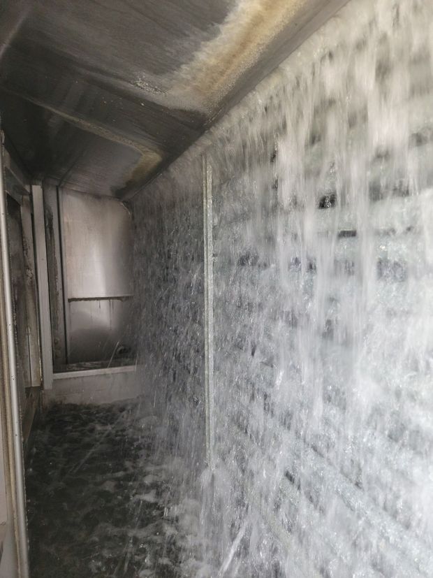 Water streaming down a narrow industrial corridor with white walls and a dark floor