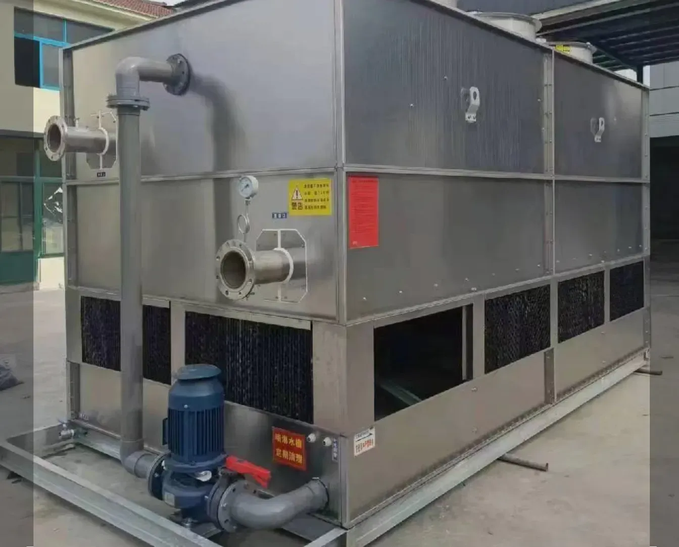 Industrial HVAC unit with gray metal корпус and blue pump on a concrete pad outdoors
