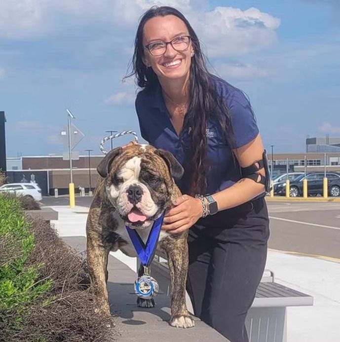 A woman is holding a dog with a medal around its neck